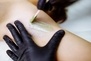 Professional esthetician performing a waxing treatment in a clean spa treatment room